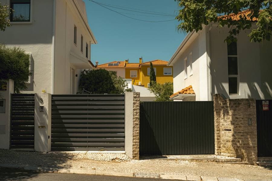 Two modern dark metal gates in front of white houses